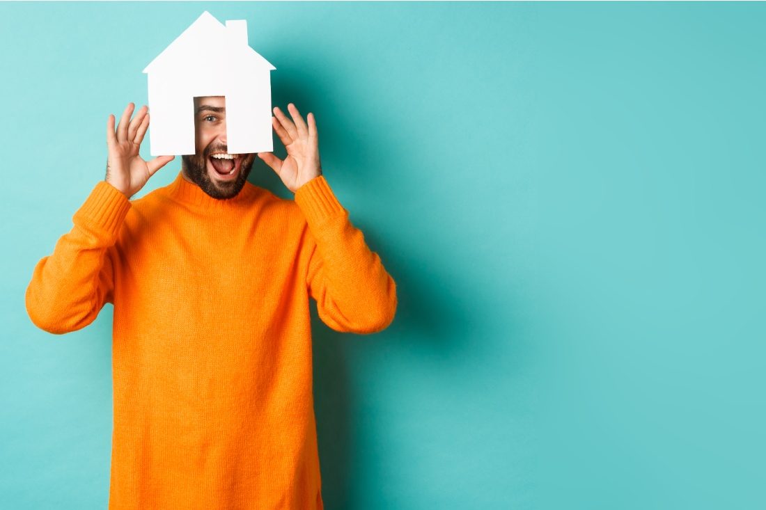 Ważny jest również standard wykończenia  Mężczyzna w pomarańczowym swetrze trzyma papierowy dom